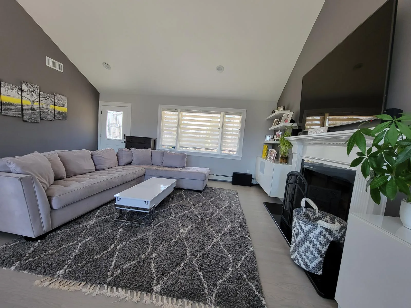 Freshly cleaned living room with a grey sectional sofa, fireplace and vaulted ceiling