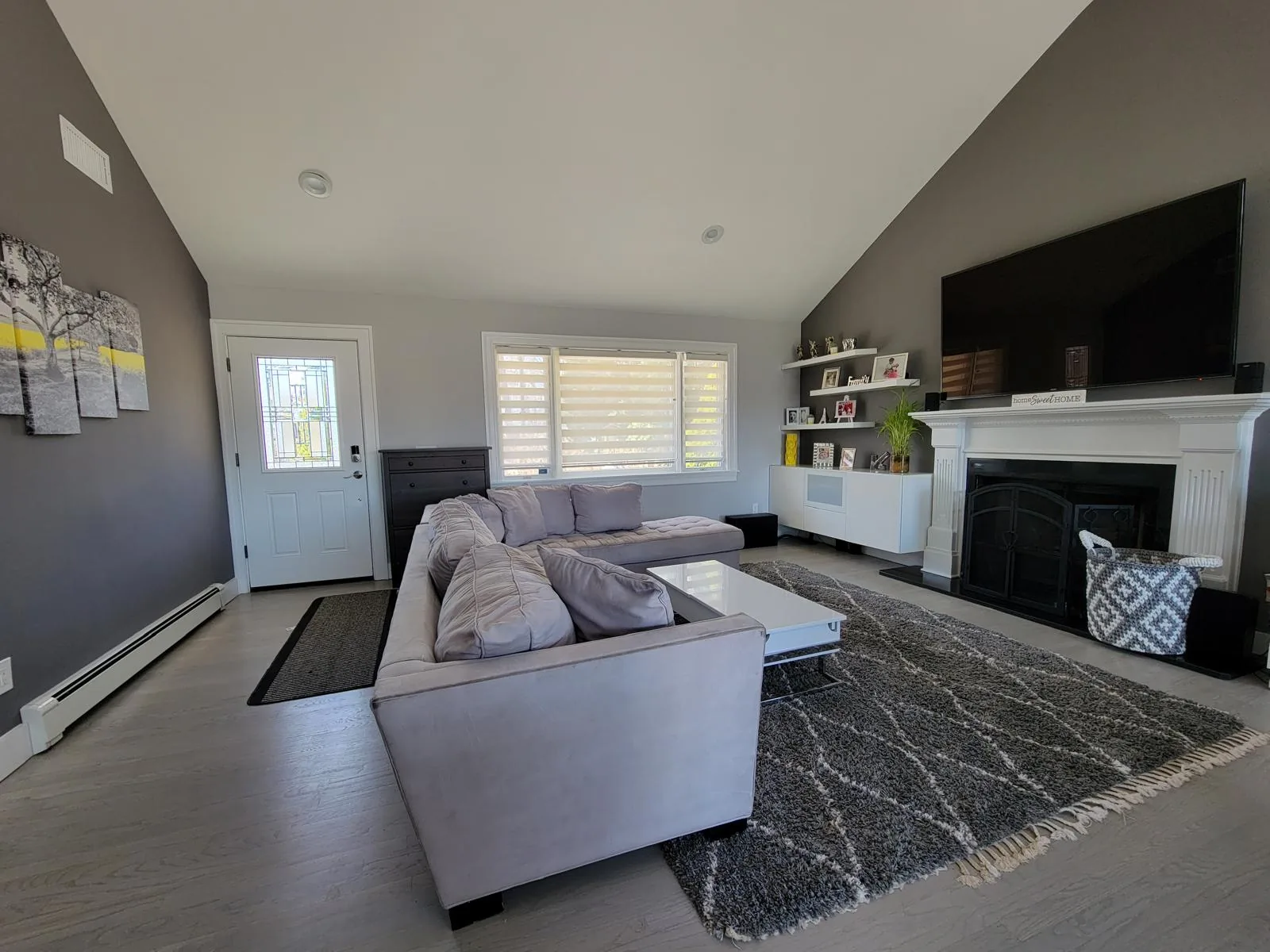 Spotless open-plan living room with a sectional sofa, patterned rug and white fireplace