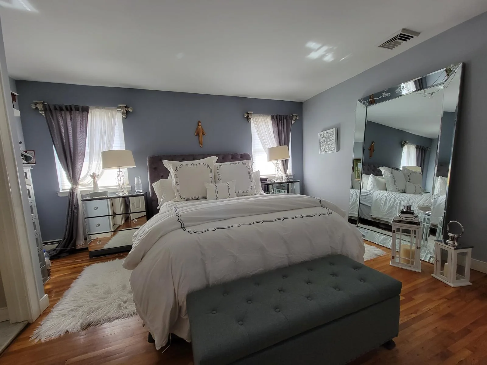 Freshly made master bedroom with crisp white bedding and hardwood floors